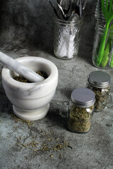 Grinding dried herbs in a marble mortar and pestle to use over the winter. Space for text.