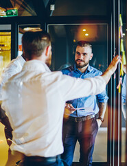 Creative employees discussing working strategy standing near glass wall sharing ideas