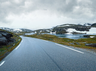 Summer mountain misty landscape with road, lake and snow (Norway, Aurlandsfjellet).