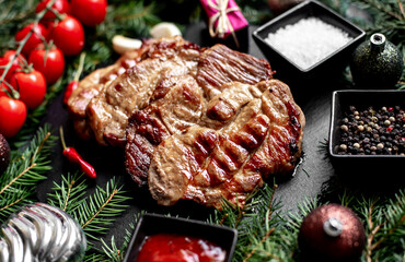 Christmas grilled pork steaks on a background of a Christmas tree and Christmas decorations with copy space for your text