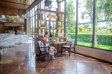 Leisure in urban eatery, person holding menu, elegantly seated in patterned summer dress, modern wooden interior design.