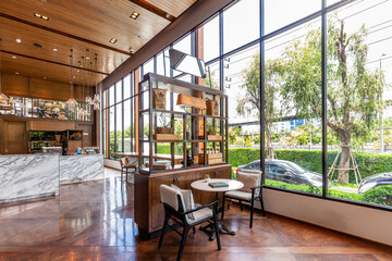 Modern cafe interior with large windows, wooden furniture, marble countertop, hanging bulbs, and...