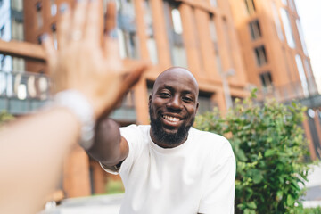 Cheerful black man giving high five to crop friend