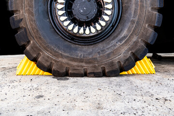 A pair of yellow safety wheel chock stopping an industrial vehicle from moving