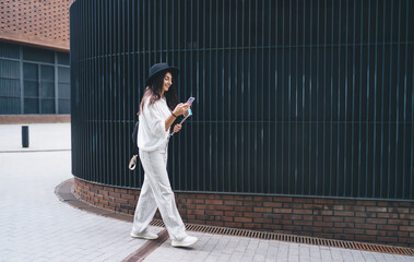 Joyful woman using smartphone while walking on street