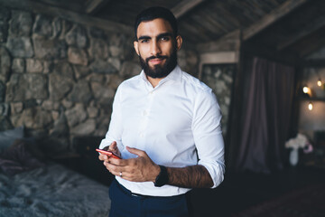 Smiling man with cellphone in dark apartment