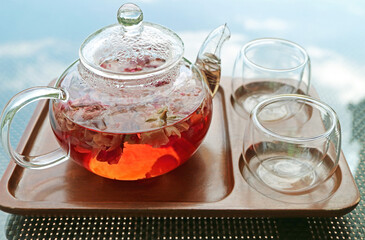 Closeup of a pot of rose infusion tea with a pair of tea cups