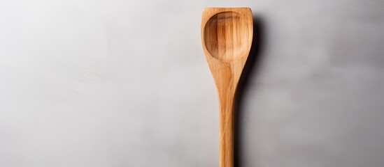 A gray background showcases a wooden spatula for use in the kitchen