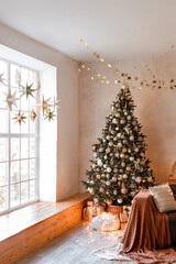 Interior of modern living room with comfortable sofa decorated with Christmas tree and gifts