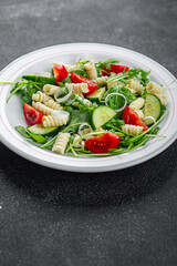 pasta salad fusilli pasta, cucumber, tomato, green lettuce cooking eating appetizer meal food snack on the table copy space food background rustic top view keto or paleo diet vegetarian