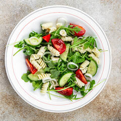 pasta salad fusilli pasta, cucumber, tomato, green lettuce cooking eating appetizer meal food snack on the table copy space food background rustic top view keto or paleo diet vegetarian
