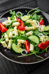 pasta salad fusilli pasta, cucumber, tomato, green lettuce cooking eating appetizer meal food snack on the table copy space food background rustic top view keto or paleo diet vegetarian