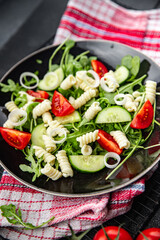 pasta salad fusilli pasta, cucumber, tomato, green lettuce cooking eating appetizer meal food snack on the table copy space food background rustic top view keto or paleo diet vegetarian