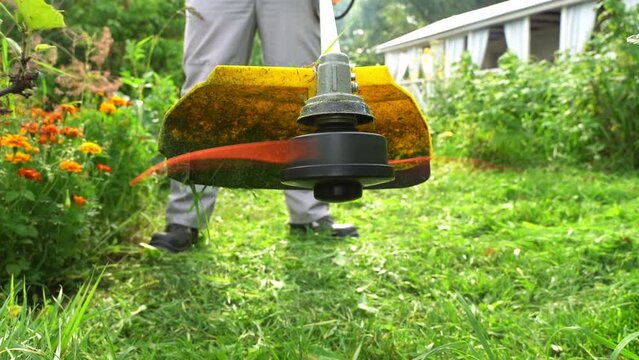 a man mows the grass with a grass trimmer
