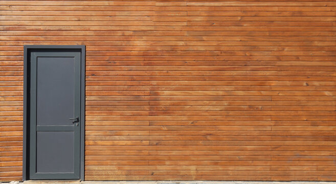 new, modern black plastic door in wooden garage , house building. Home,  exterior. front view.