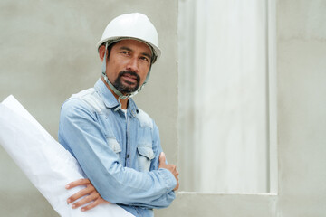 Employees multiethnic construction workers engineers wearing safety helmets Standing arms crossed holding diagram work's structure Looking camera take photo   cement wall supervising construction wor