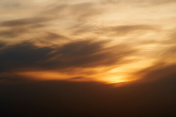 Obraz premium Sunset sky with red light of the setting sun. Evening clouds in the orange light of sunset rays