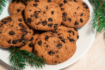 Chocolate cookies on a plate with spruce branches on the table. Dark chocolate cookies on a plate, Christmas cookies chocolate cinnamon sweet dessert holiday treat new year and christmas food
