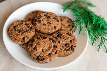 Chocolate cookies on a plate with spruce branches on the table. Dark chocolate cookies on a plate, Christmas cookies chocolate cinnamon sweet dessert holiday treat new year and christmas food
