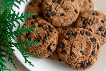 Chocolate cookies on a plate with spruce branches on the table. Dark chocolate cookies on a plate, Christmas cookies chocolate cinnamon sweet dessert holiday treat new year and christmas food