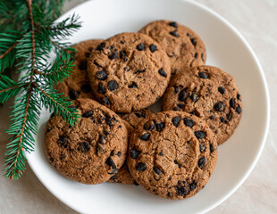 Chocolate cookies on a plate with spruce branches on the table. Dark chocolate cookies on a plate, Christmas cookies chocolate cinnamon sweet dessert holiday treat new year and christmas food