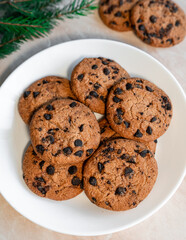 Chocolate cookies on a plate with spruce branches on the table. Dark chocolate cookies on a plate, Christmas cookies chocolate cinnamon sweet dessert holiday treat new year and christmas food
