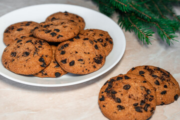 Chocolate cookies on a plate with spruce branches on the table. Dark chocolate cookies on a plate, Christmas cookies chocolate cinnamon sweet dessert holiday treat new year and christmas food