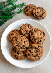 Chocolate cookies on a plate with spruce branches on the table. Dark chocolate cookies on a plate, Christmas cookies chocolate cinnamon sweet dessert holiday treat new year and christmas food