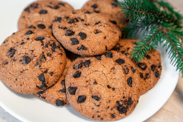 Chocolate cookies on a plate with spruce branches on the table. Dark chocolate cookies on a plate, Christmas cookies chocolate cinnamon sweet dessert holiday treat new year and christmas food