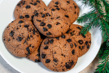 Chocolate cookies on a plate with spruce branches on the table. Dark chocolate cookies on a plate, Christmas cookies chocolate cinnamon sweet dessert holiday treat new year and christmas food