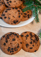 Chocolate cookies on a plate with spruce branches on the table. Dark chocolate cookies on a plate, Christmas cookies chocolate cinnamon sweet dessert holiday treat new year and christmas food
