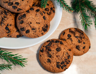 Chocolate cookies on a plate with spruce branches on the table. Dark chocolate cookies on a plate, Christmas cookies chocolate cinnamon sweet dessert holiday treat new year and christmas food