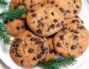 Chocolate cookies on a plate with spruce branches on the table. Dark chocolate cookies on a plate, Christmas cookies chocolate cinnamon sweet dessert holiday treat new year and christmas food
