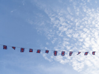 A line of Union Jack bunting flags, stretched across a summer sky.