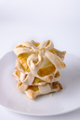 homemade puff pastry cookies with apple, on a white plate, copy space