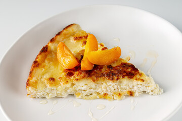 triangular piece of cheesecake with honey and apricots on a white plate