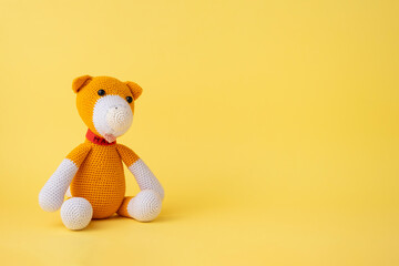 Amigurumi of a dog on a yellow background. Copy space