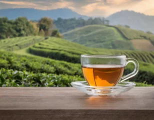 Foto op Plexiglas glass teacup on the wooden table and the background of tea plantations © gary