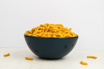 pasta horns in a deep blue bowl on a white background