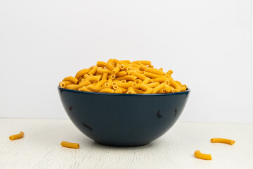 pasta horns in a deep blue bowl on a white background