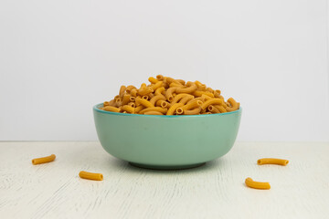 pasta horns in a green bowl on a white background