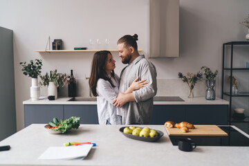 Loving couple hugging in kitchen during weekend