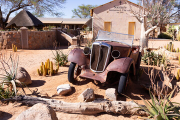 Old car wreck in front of the modest 1951 Immanuel Church in the remote town of Solitaire, Namibia,...