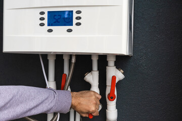 Worker hand remote or installing double-circuit gas boiler for winter home heating and water...