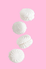 Soaring white zephyr marshmallow on pink background, food levitation