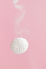 Soaring white zephyr marshmallow on pink background with sugar powder flying food levitation