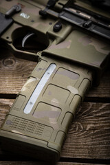 A modern carbine with an optical sight and a silencer. Weapons in camouflage coloring. Old wooden...