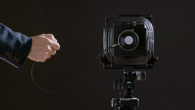 Photography courses and photography training. Cock the camera and take photographs in the studio. Classic camera, gimbal camera with compur lens. Black camera on a black background.