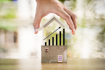 Woman hand hold to open a roof and black arrow graph chart on transparent screen with growing value substantial savings money in the public park, Business investment or loan for real estate concept.