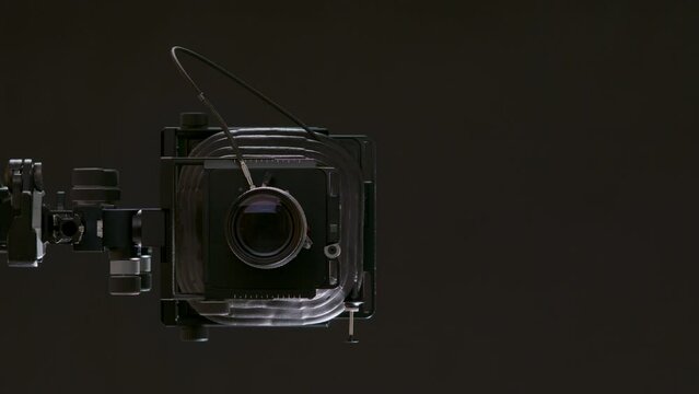 A man measures the lighting with an exposure meter, cocks the camera and takes photographs. Professional classic photo camera in the studio. Photo school and photography training. Vertical video.